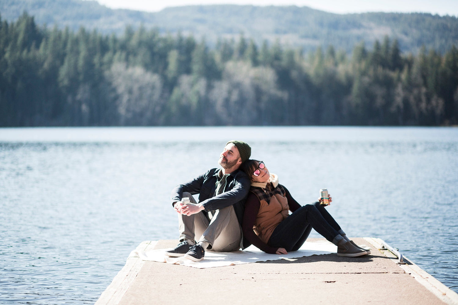 A couple leaning against each other on the dock of a lake, wearing SAOLA shoes